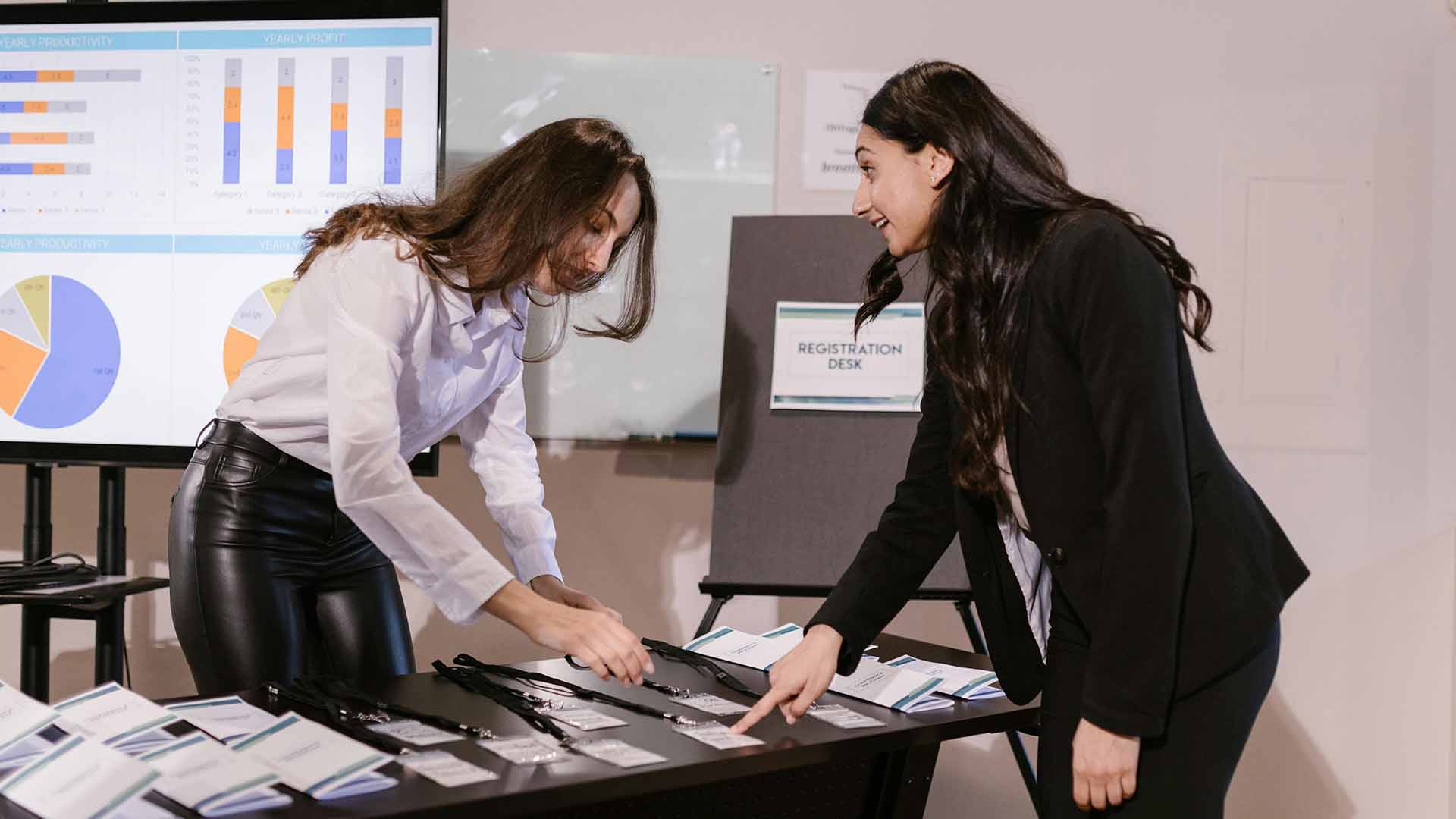 Preparación de lanyards ecológicos en mostrador de registro de eventos corporativos para acciones de employer branding.
